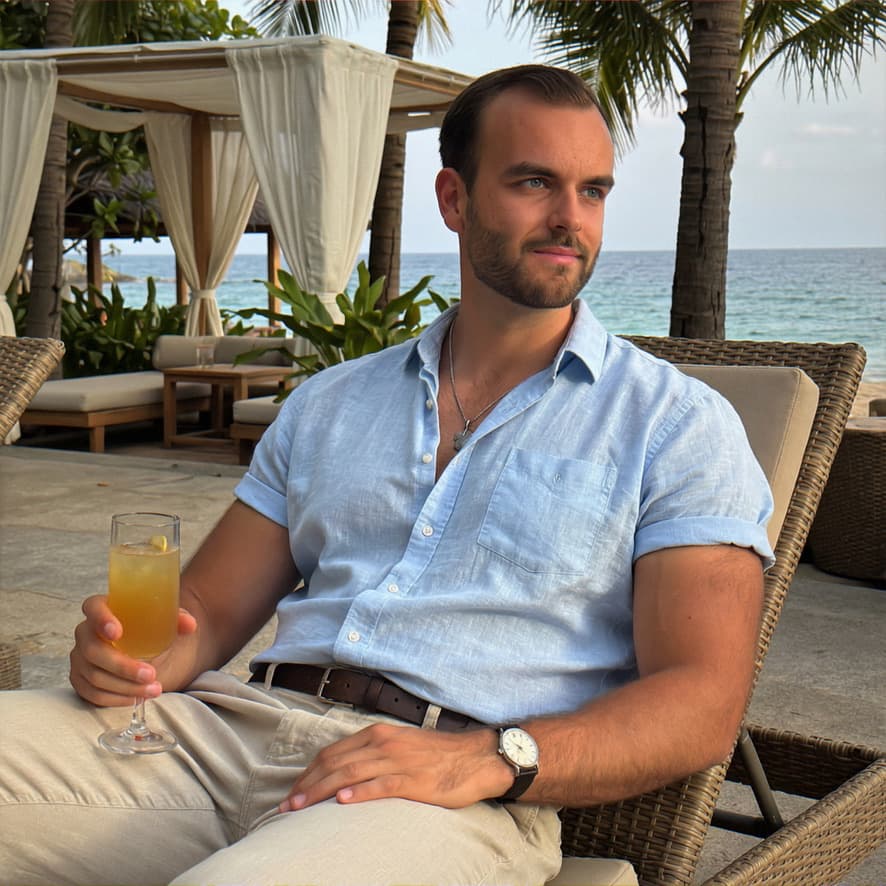 Man at a beach resort in a light blue shirt, relaxed expression — example of a clear face shot for a dating profile