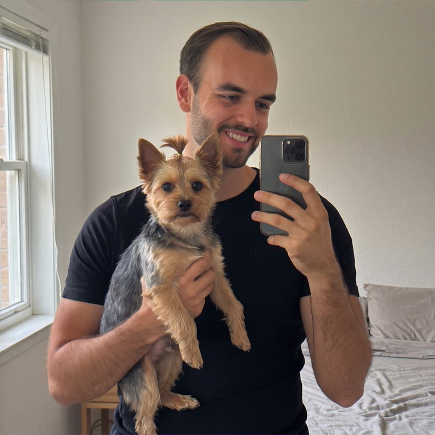 Mand, der holder en lille Yorkie-hund og smiler — eksempel på med-husdy-foto til datingprofil